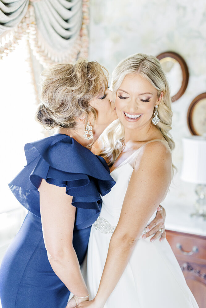 mom kissing bride before wedding