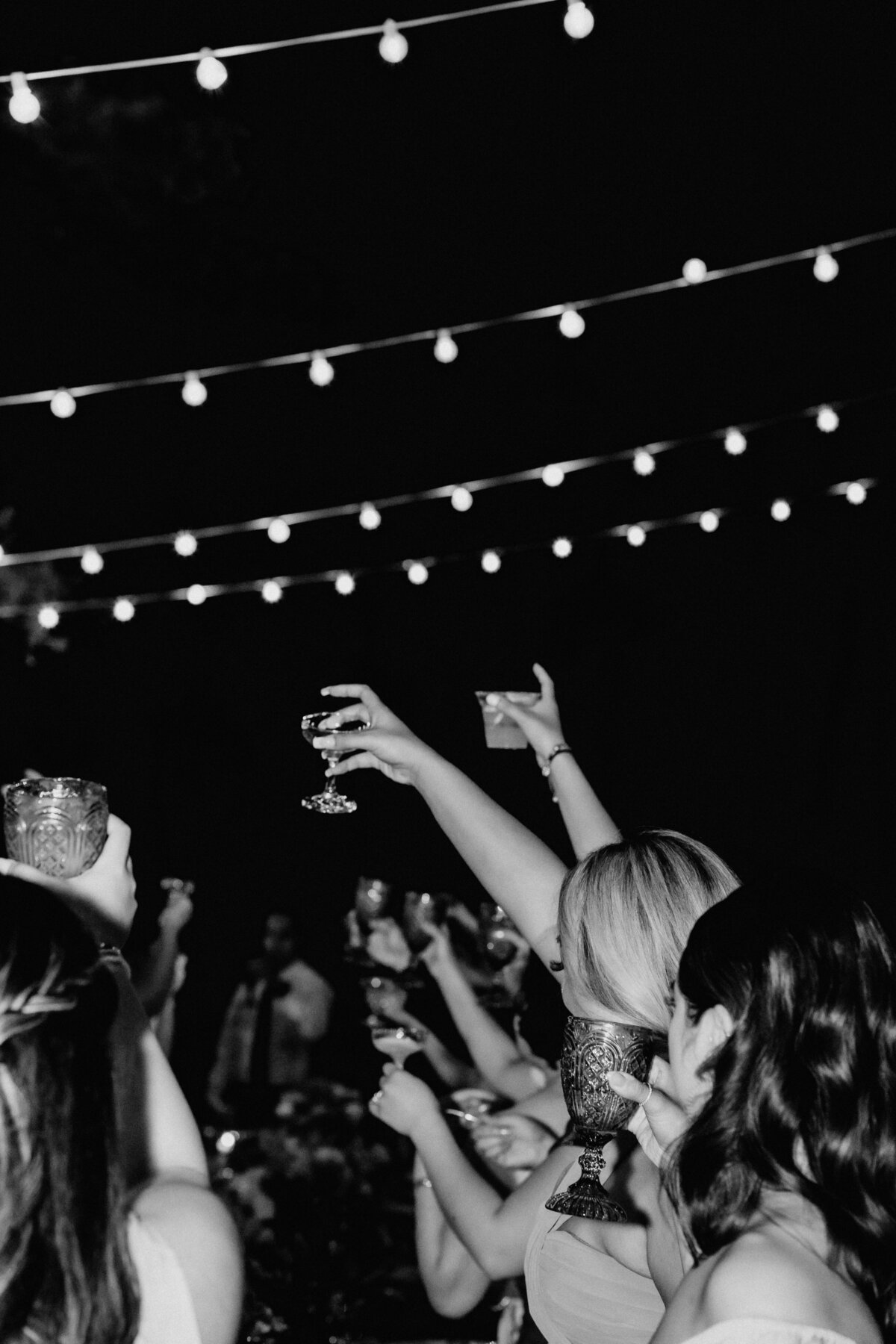 Black and white arms raised holding glasses fo ra cheers