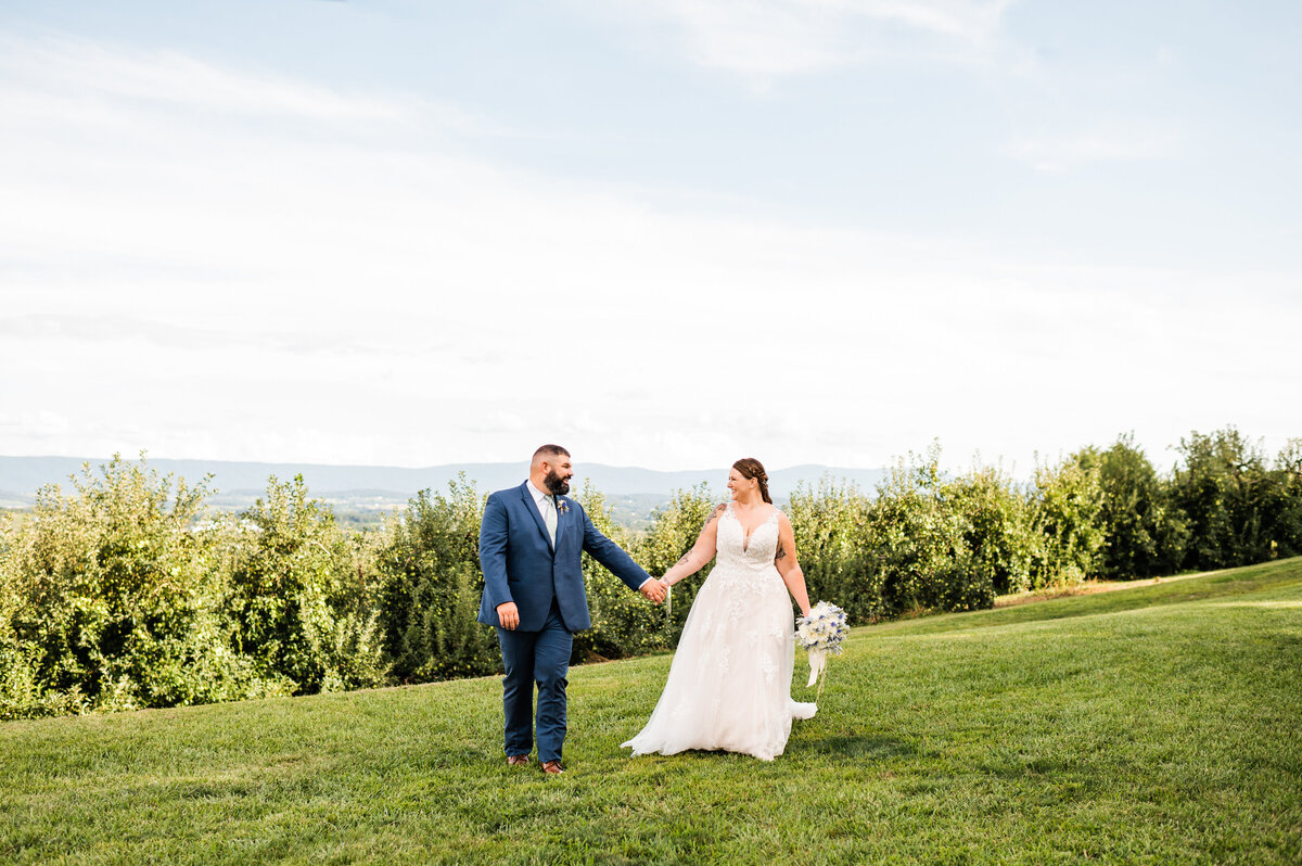 Virginia wedding photographer captures bride adn groom portraits outdoors for a Shenadoah wedding with the couple holding hands and laughing on the lawn of the wedding venue