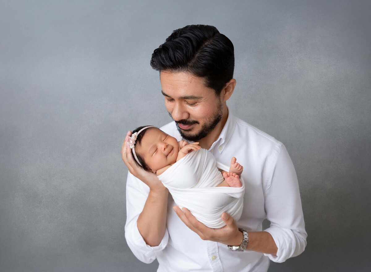 Newborn baby girl held by the father both smiling  first pictures together