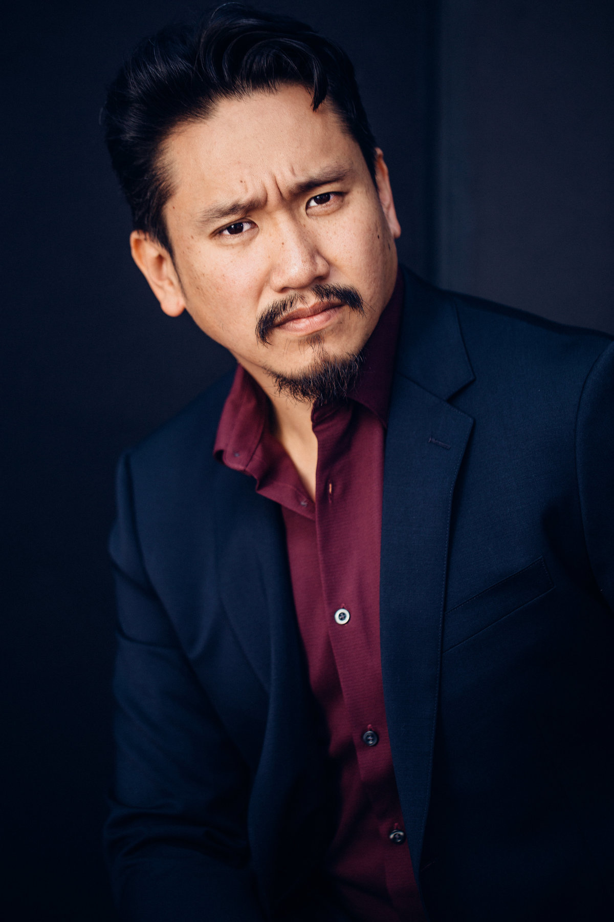 Headshot Photograph Of Man In Outer Black Suit And Inner Maroon Long Sleeves Los Angeles