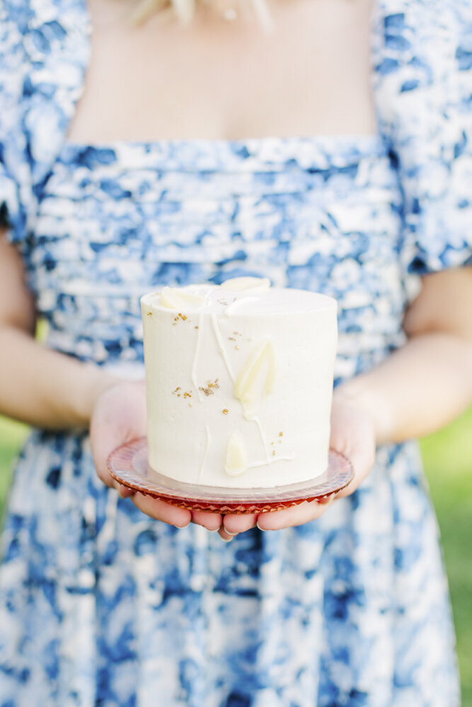 woman holding a small, white wedding cake