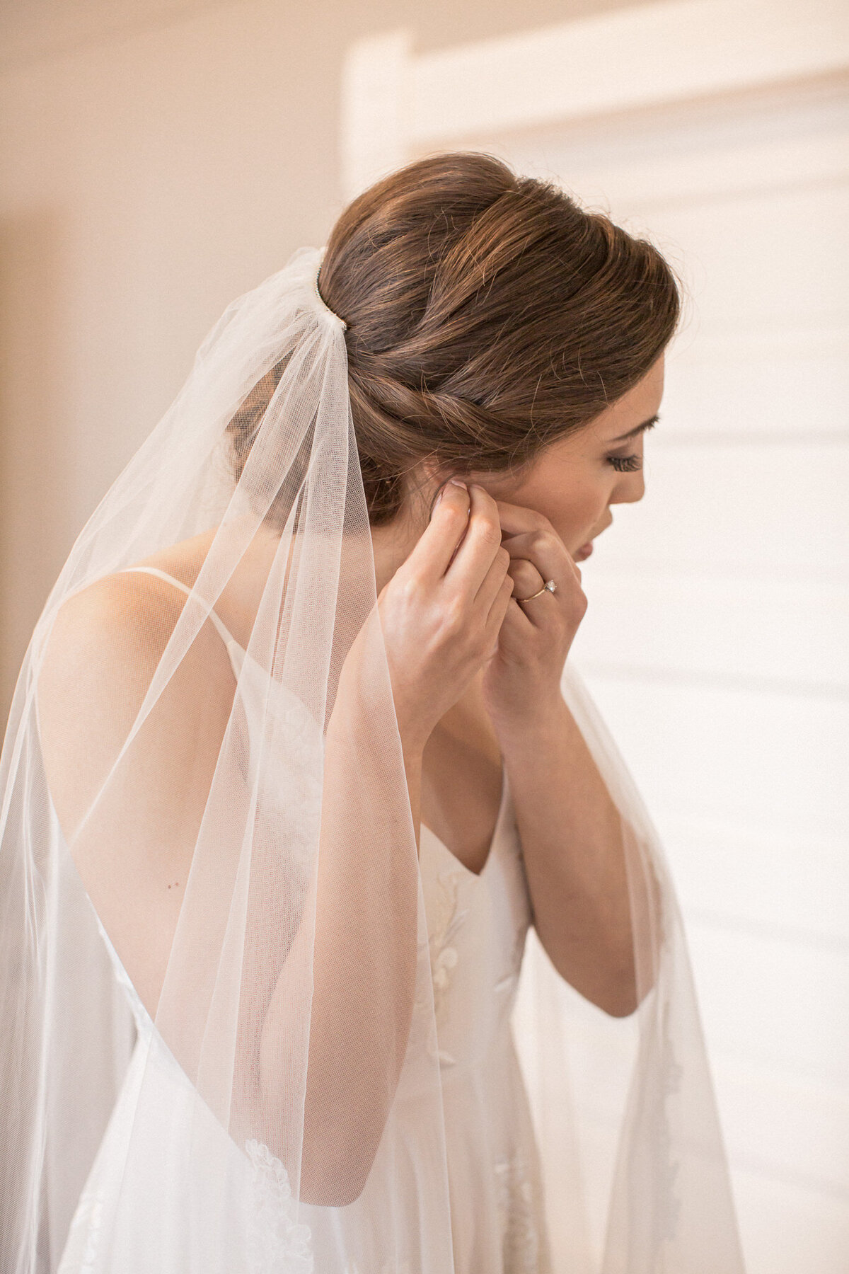the bride puts in her earrings just moments before walking down the aisle on her wedding day
