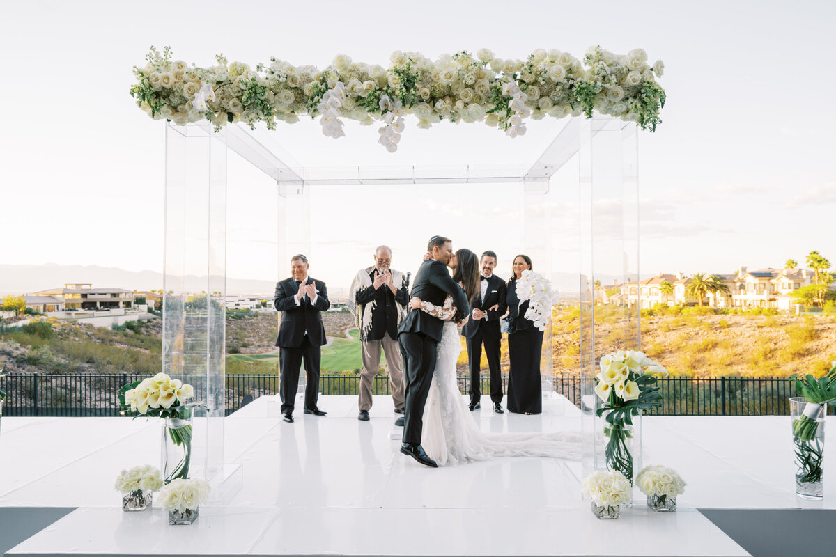 Bride and groom have their first kiss as a married couple under luxe chuppah overlooking Las Vegas