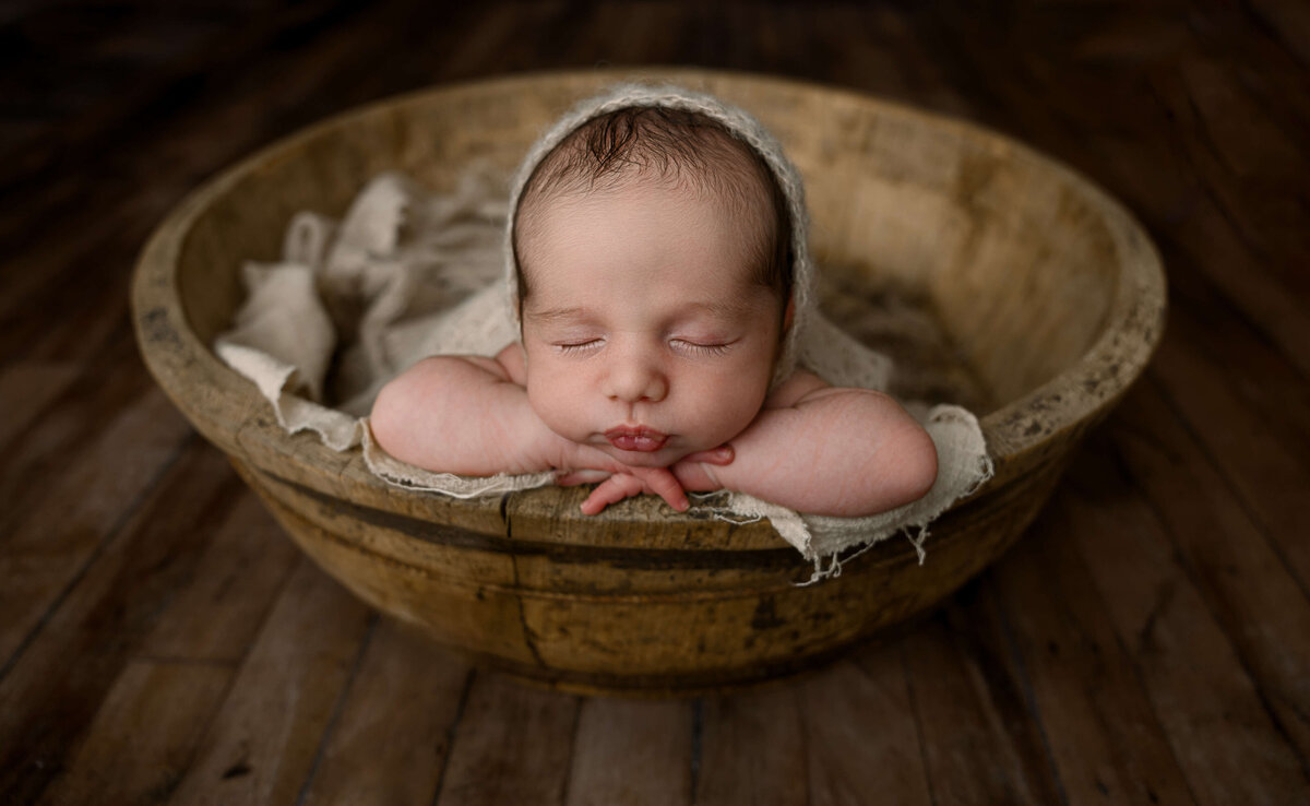 Gorgeous newborn baby boy in an antique bowl in an Erie photography studio