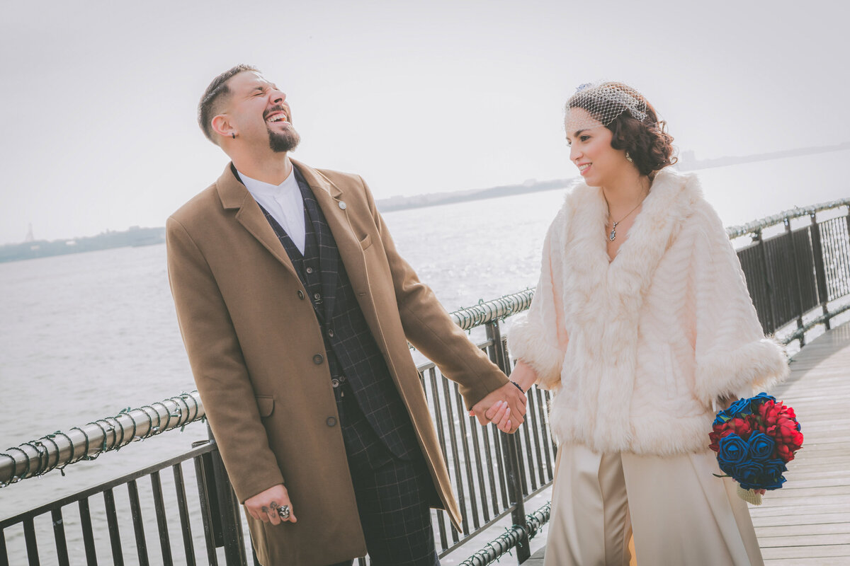 A groom laughs while wife looks on during Jersey City wedding.