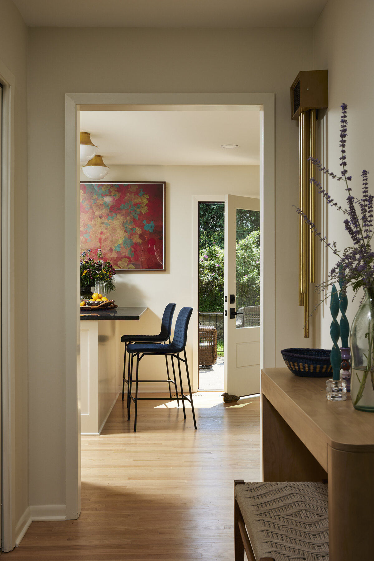 Hallway from front entry foyer to kitchen through doorway with door to back yard, kitchen island peninsula