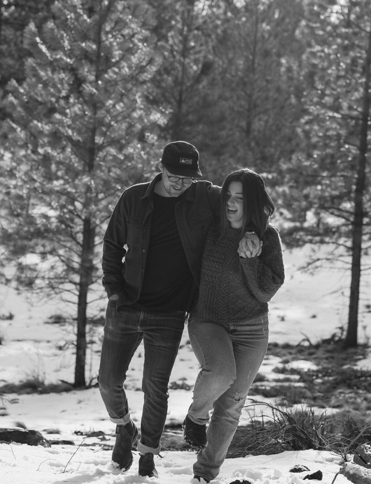 engaged couple playfully walks along a snowy trail while embracing each other in Bend, Oregon