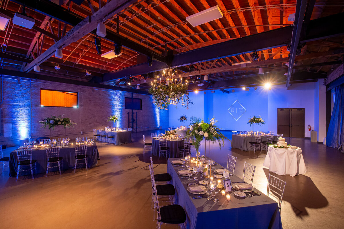 A large room with tables and chairs set up for a wedding reception