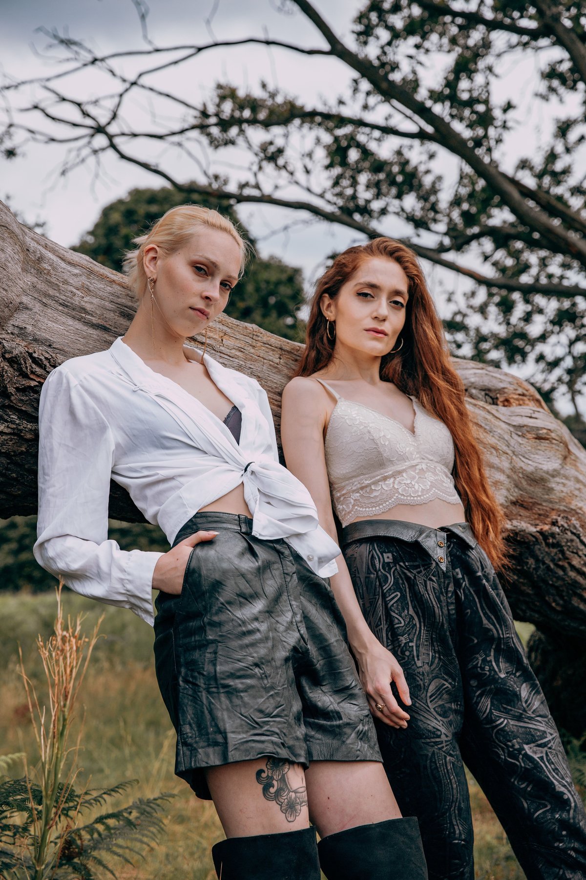 Amber and Jasmine dressed in black and white leaning against a fallen tree in Richmond Park