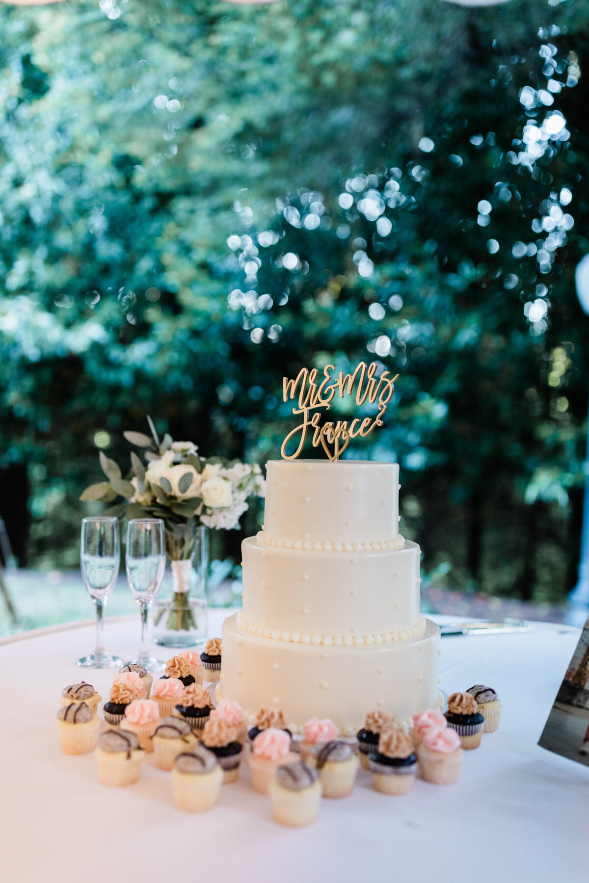 white wedding cake and pink cupcakes.