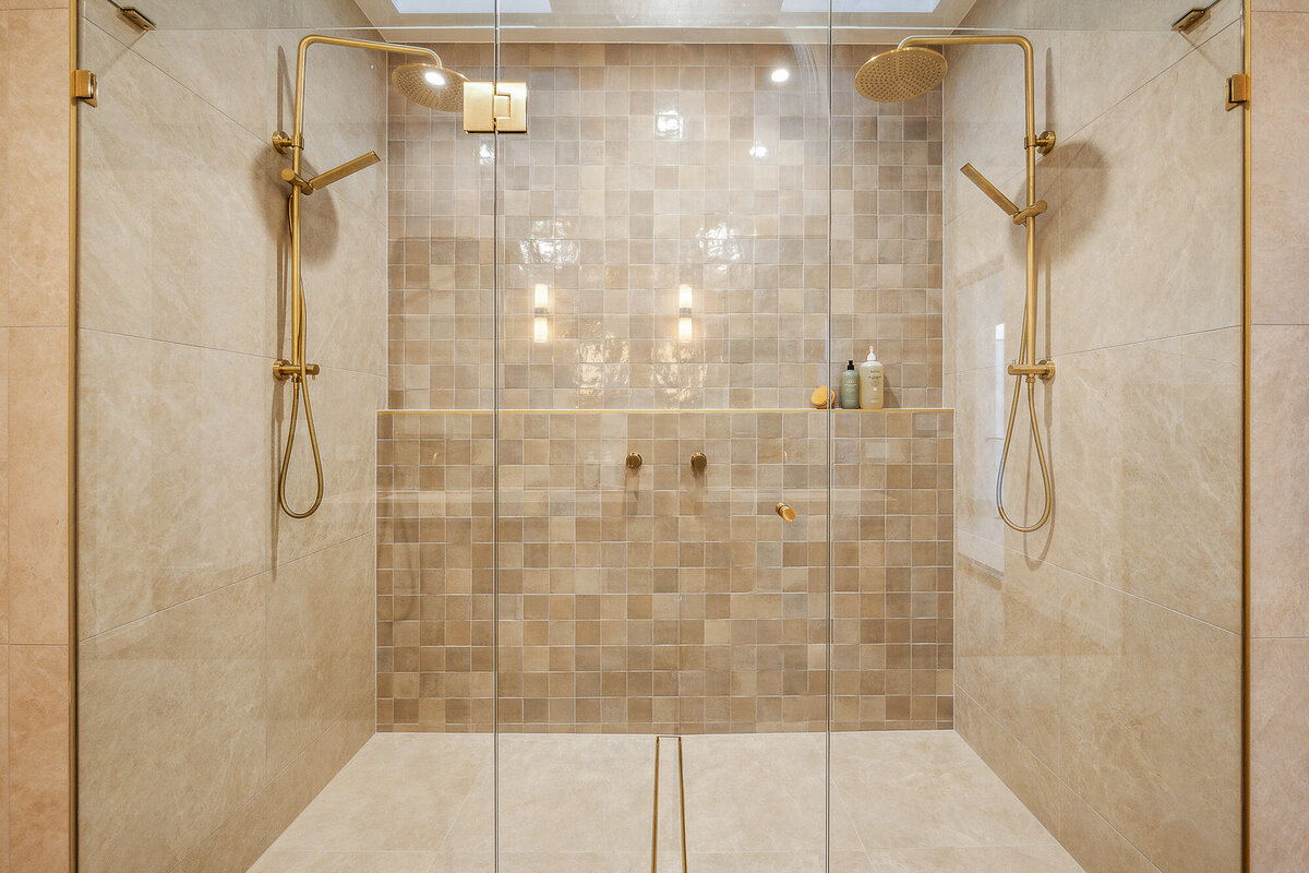 A luxurious double walk-in shower in the Marisol home, featuring warm textured tiles and brushed gold tapware.