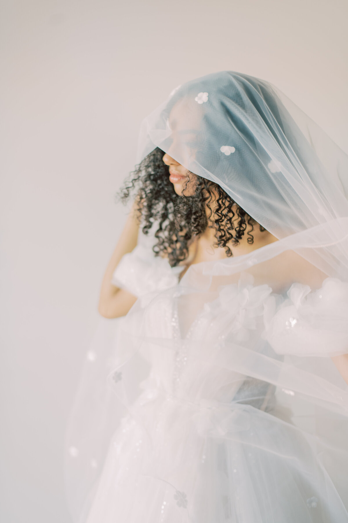 The bride with her veil cascading over her shoulders, embracing a bouquet of lush blooms, captured by Christine Grace Photography in Toronto.