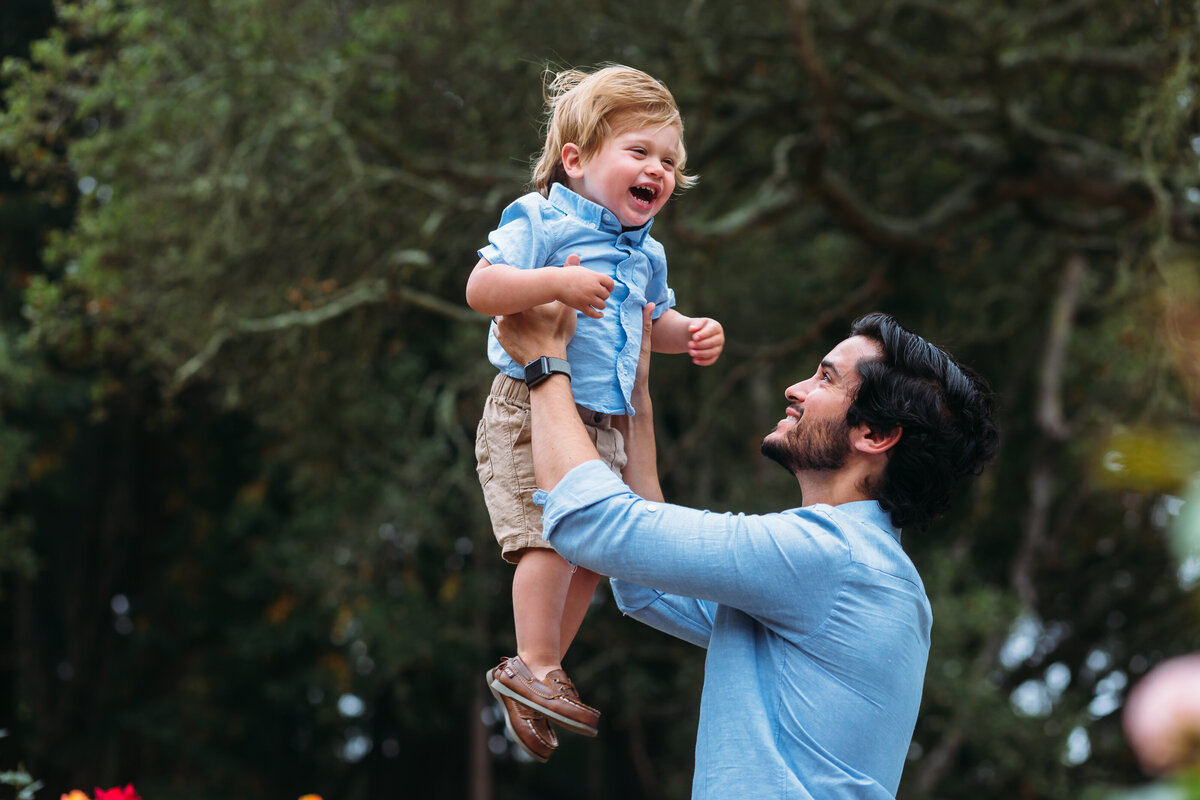 Family Photographer,  a father holds his smiling son in the air at the park