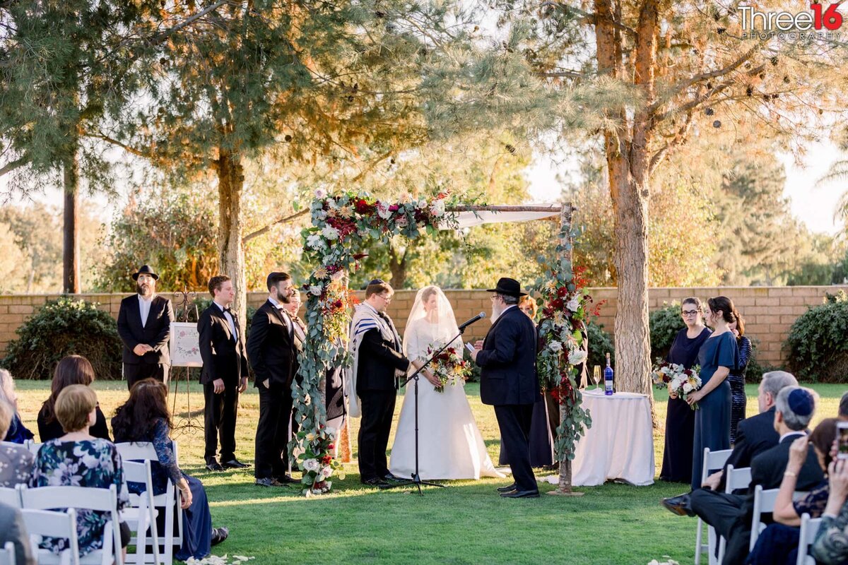 Rabbi performs a Jewish wedding ceremony as the Bride and Groom stand at attention at the altar
