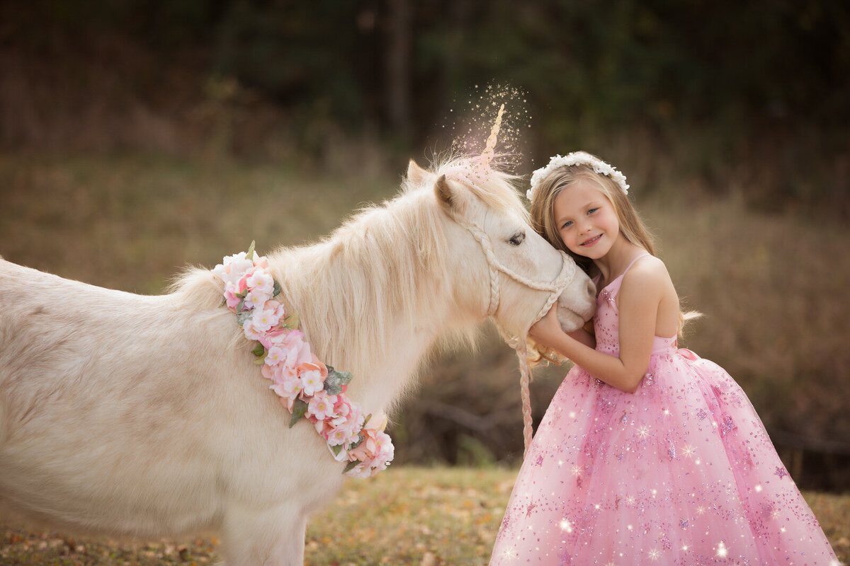 girl-in-pink-dress-hugging-unicorn -with-floral-necklace-arlington-tx