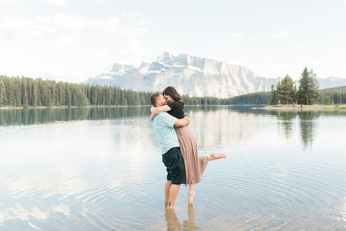 Man lifting woman in a hug in front of mountains