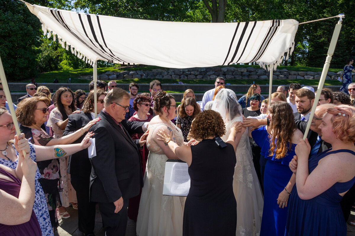LGTBQ+ couple exchanging vows under chuppah