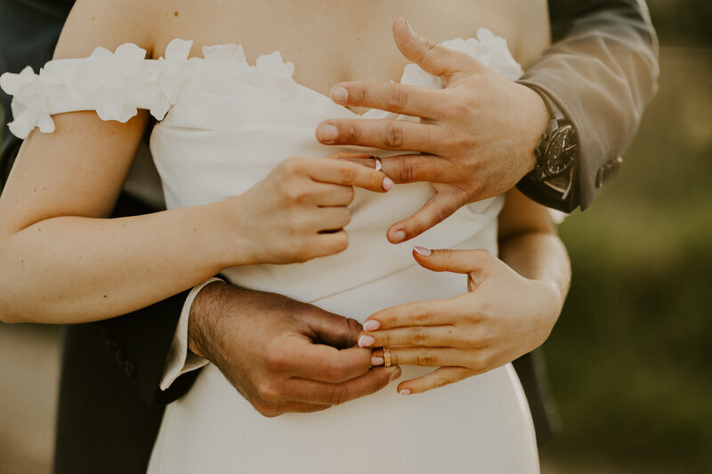 Mariés posant lors d'une séance photo de mariage et échangeant leurs alliances dans un jeu à 4 mains.