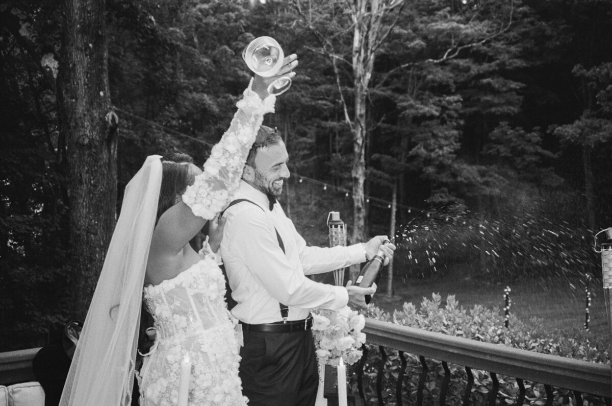 Champagne pop with couple having fun during their private backyard elopement in the Hudson Valley shot on 35mm film