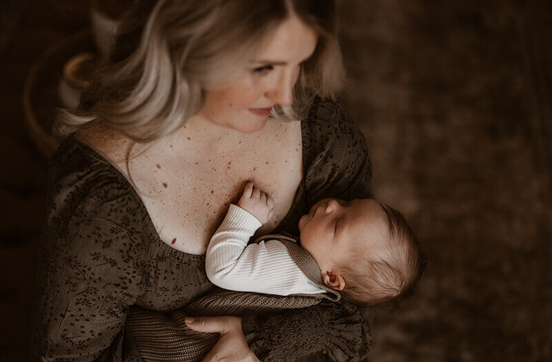 Mom snuggles baby boy against her chest in living room