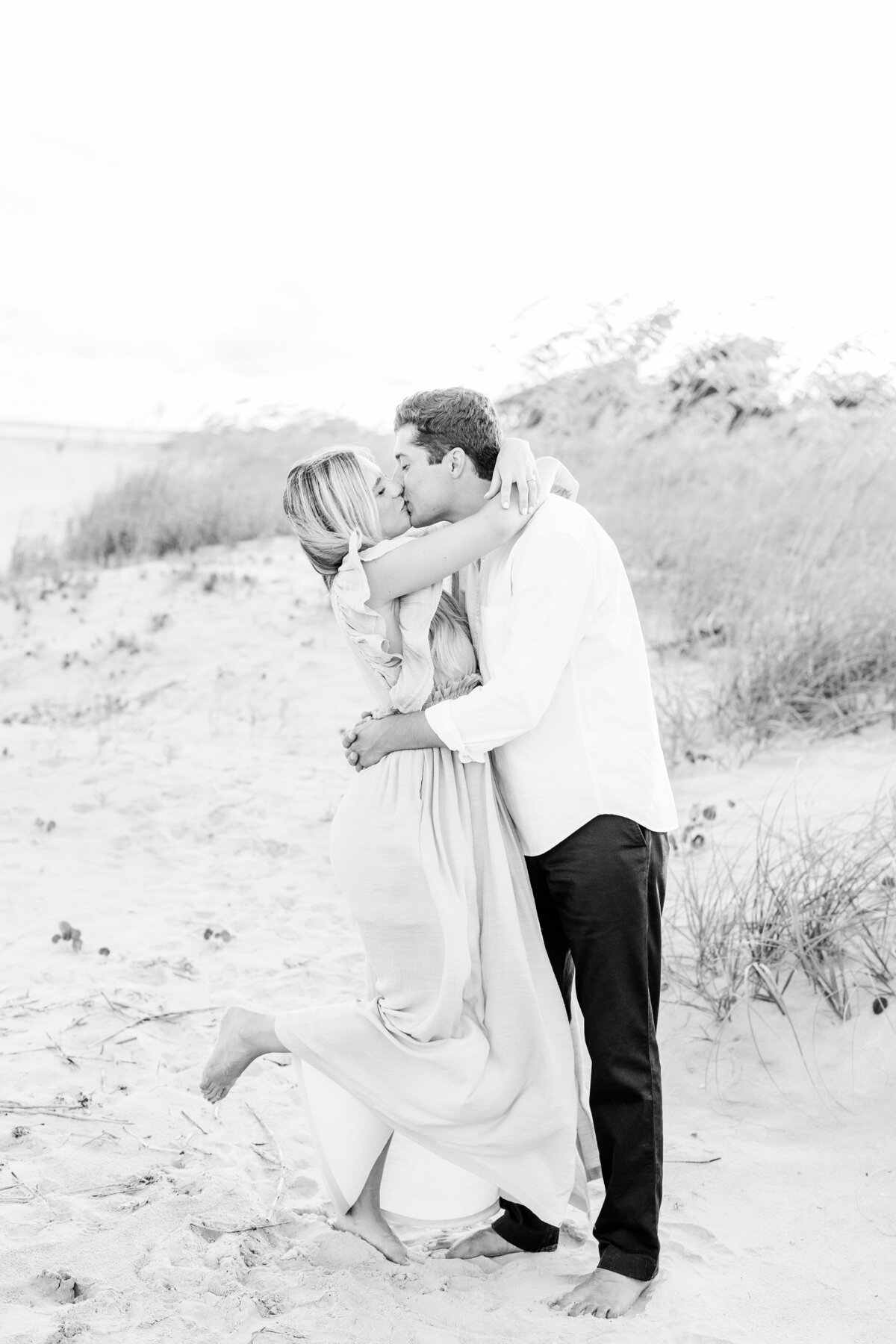 engaged couple kissing at the beach