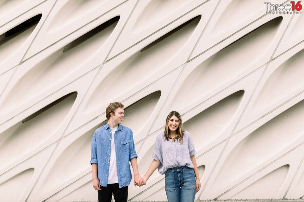 Engaged couple hold hands outside The Broad in LA