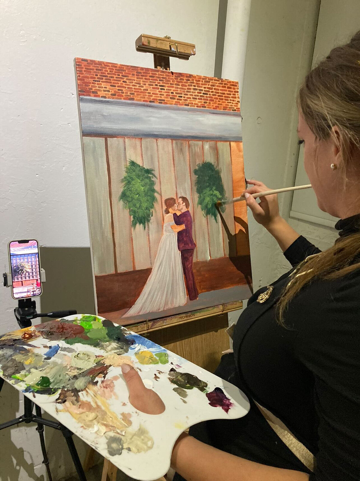 Olivia Andruss, a live wedding painter in Denver, Colorado, takes a moment to add in details to a live wedding painting