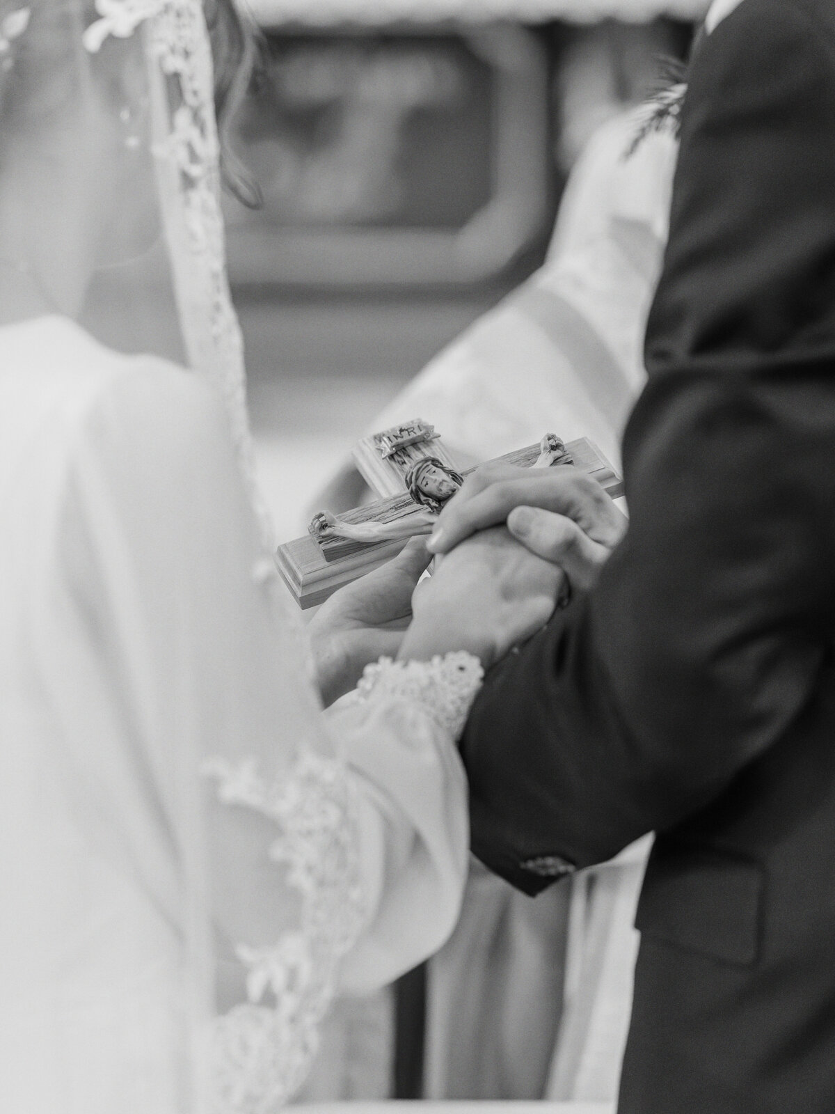 Bride and groom's hands on crucifix during Catholic wedding at Our Lady Of Victory in Rochester