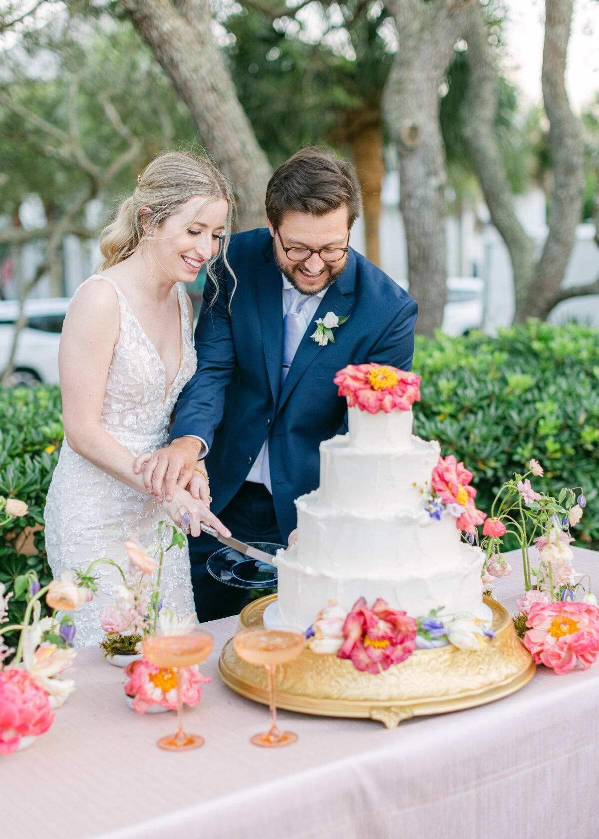 bride-groom-cutting-white-wedding-cake-blush-table