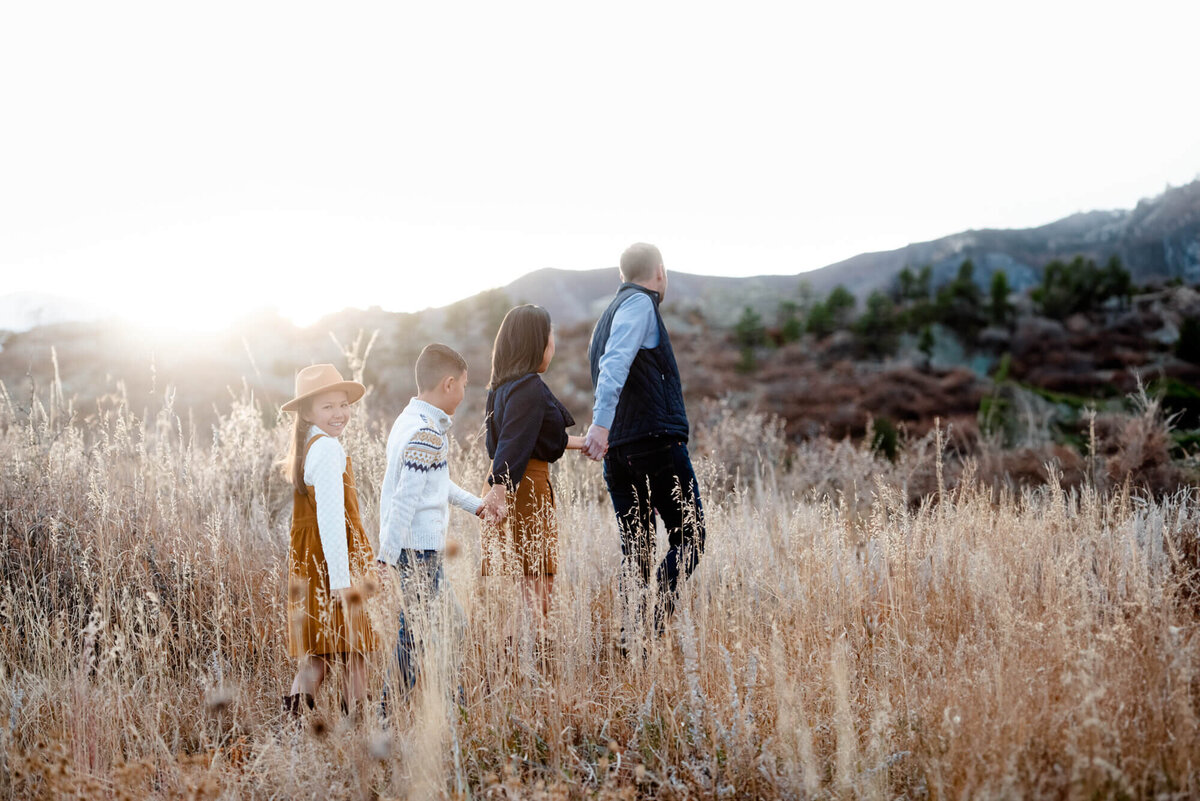 A father leads his family by the hand through trails of tall golden grass