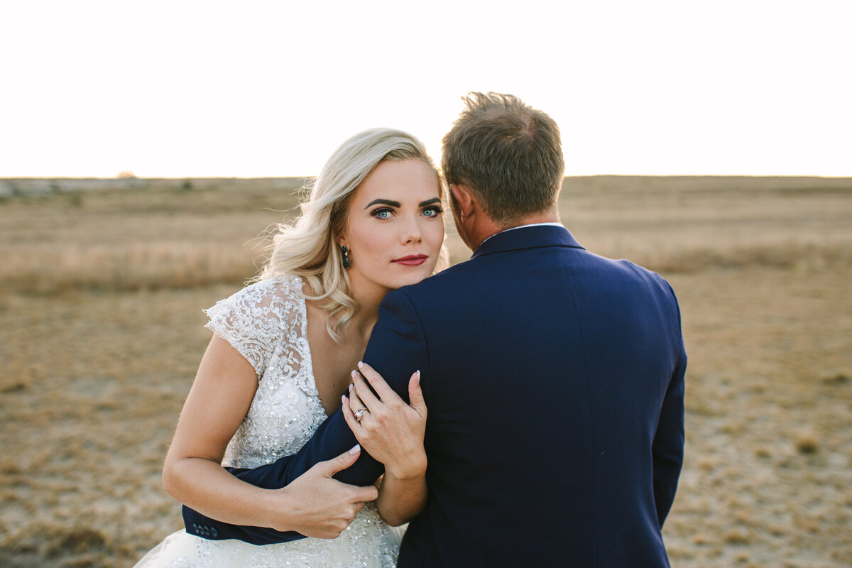 Bride leaning gently on groom’s shoulder, eyes on the camera, while groom looks away in a relaxed, documentary-style moment.