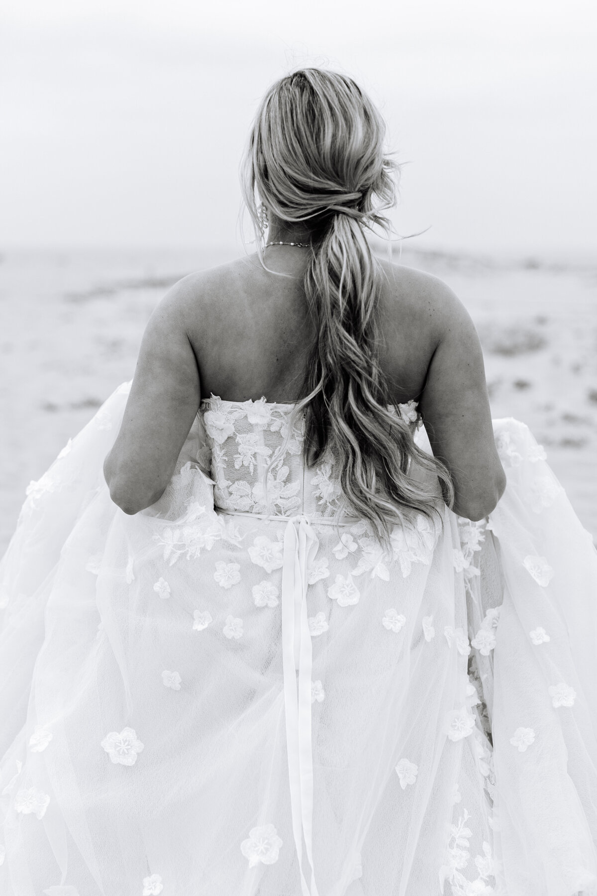 black and white image of bride facing away from camera in floral wedding gown.