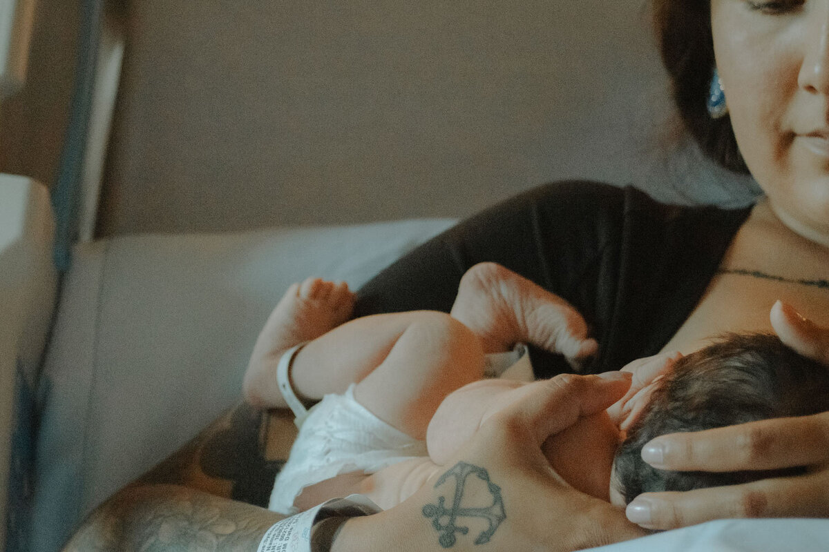 Mother nurses her newborn, holding them close with a gentle touch
