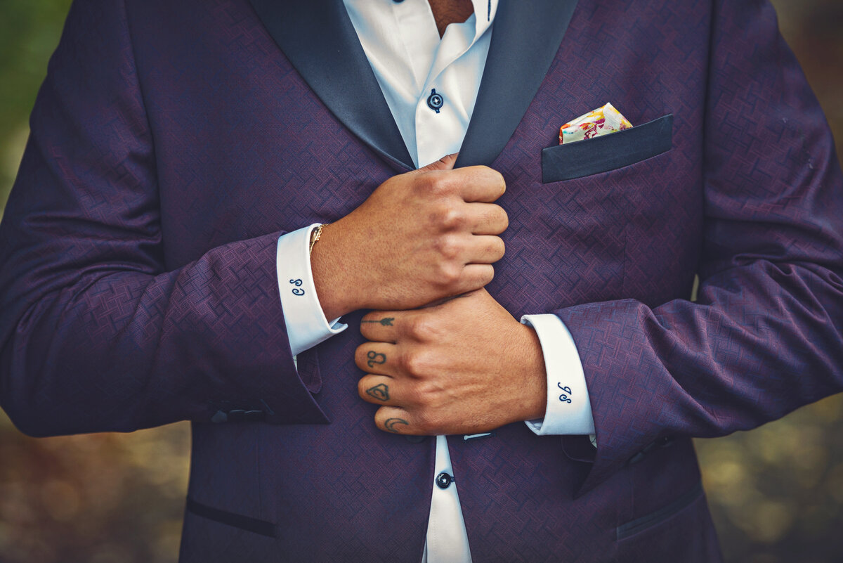 Groom hands holding unique purple wedding suit.