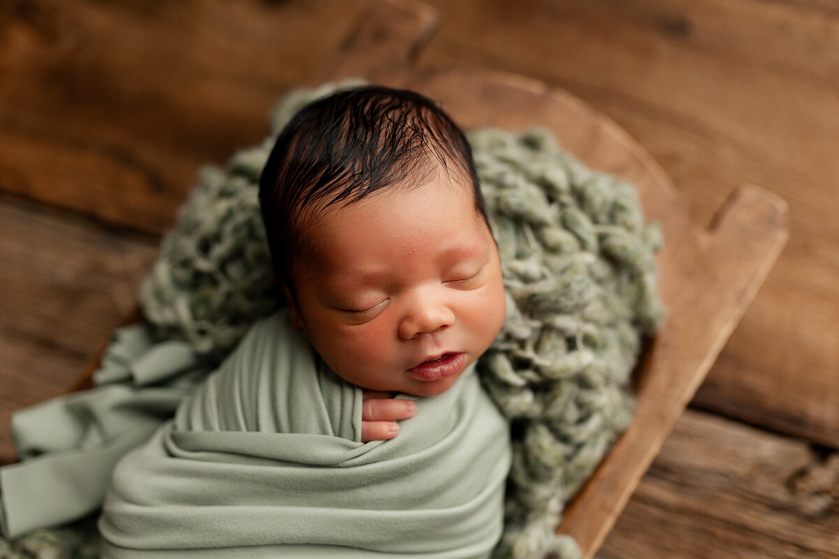 Baby boy in a pale green wrap for his newborn session.