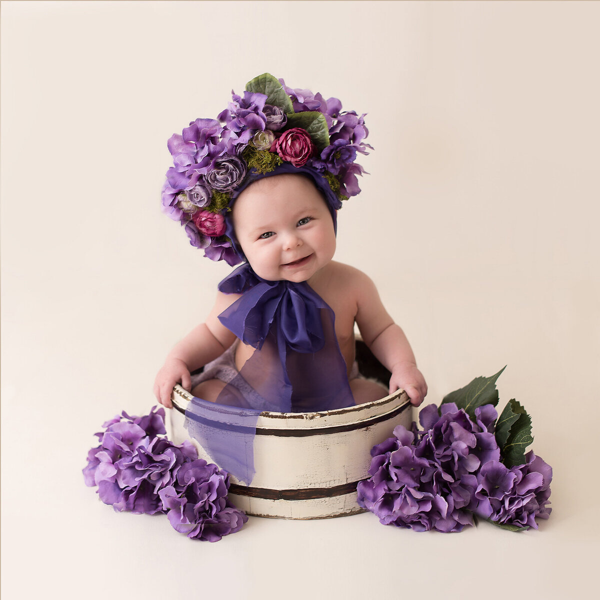 Cute little baby in a purple flowers in a bucket