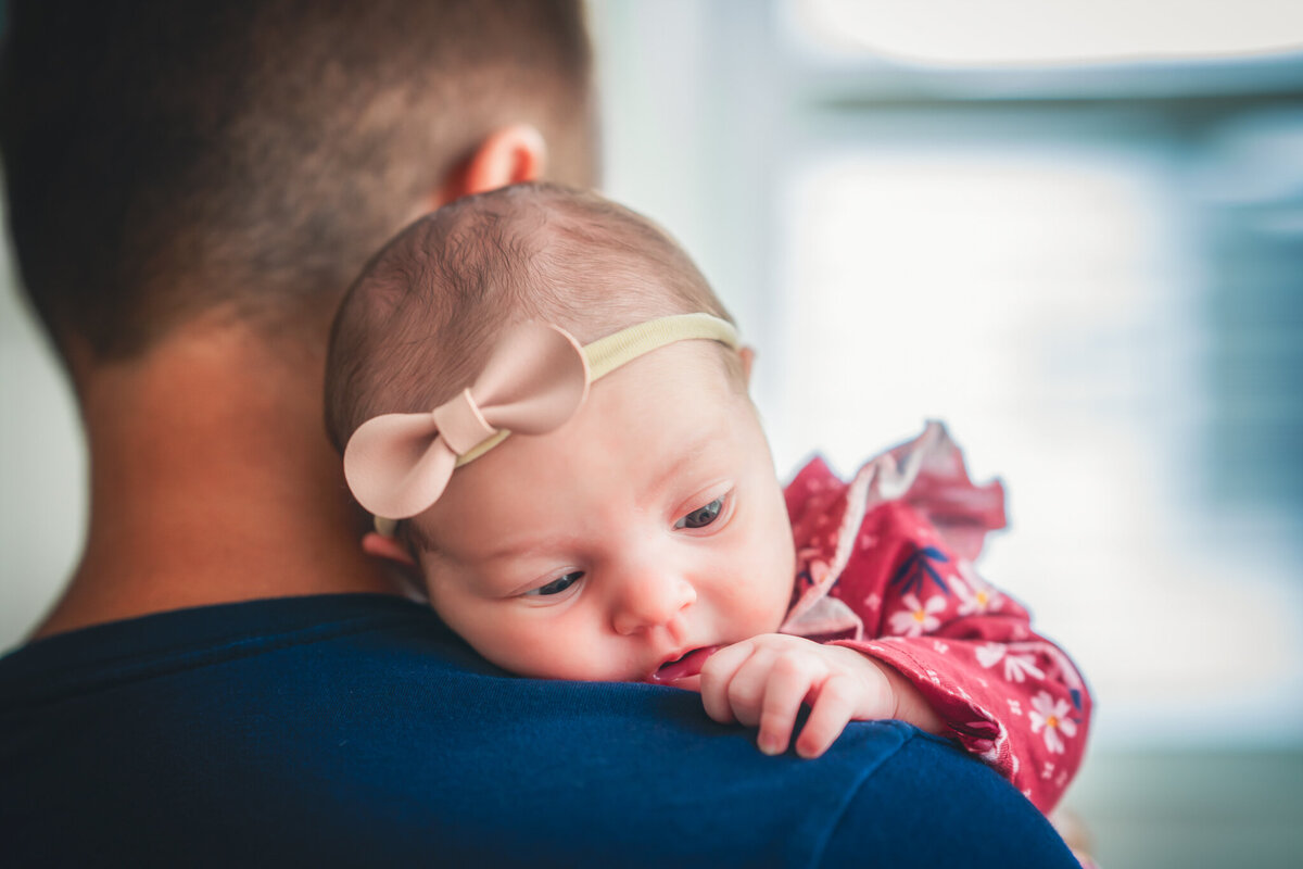 A dad in a blue shirt is holding his infant daughter.