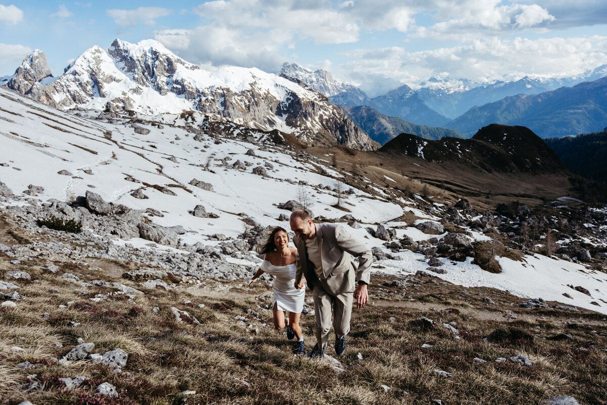 Couple smiling while walking hand in hand during mountain elopement