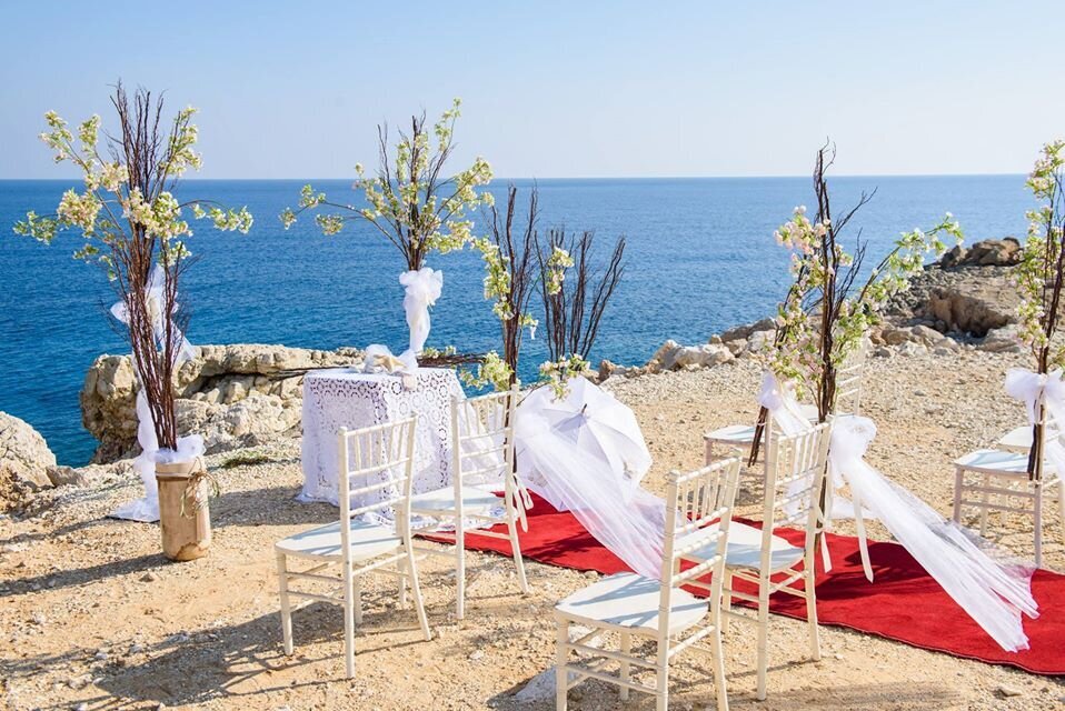 A red aisle surrounded by tall decorations and white lace overlooking the sea at the edge of a clifftop venue