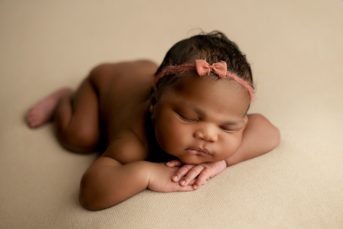 Newbron baby girl asleep chin on hands