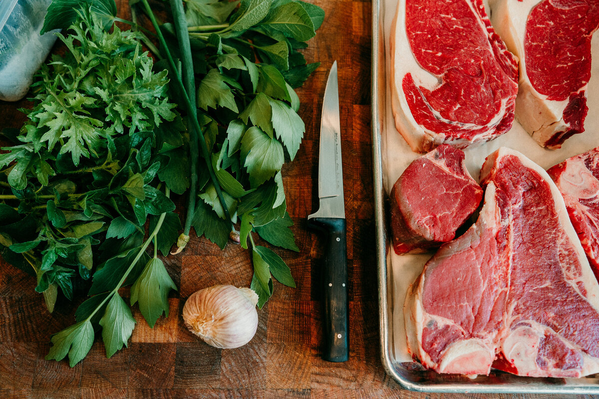 overhead photo of meat, herbs and garlic