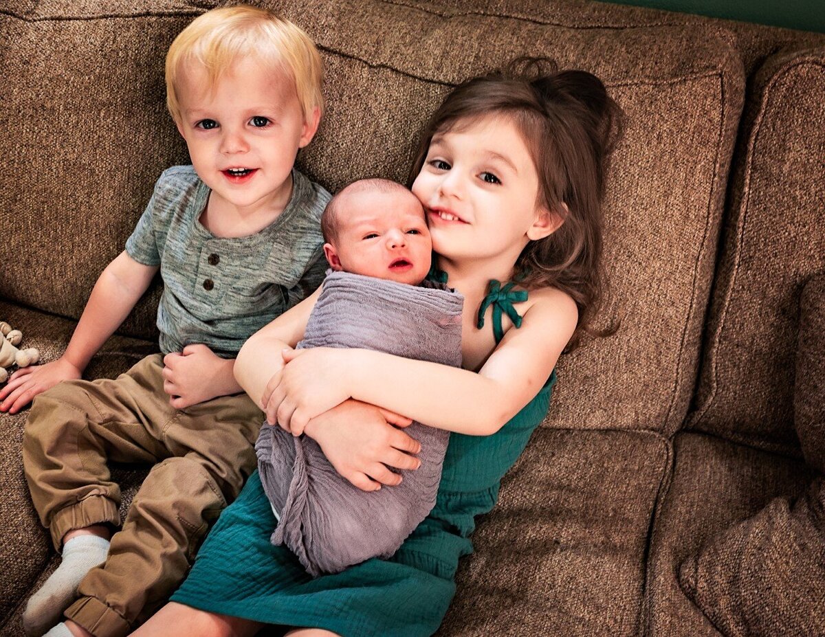 siblings holding newborn sister