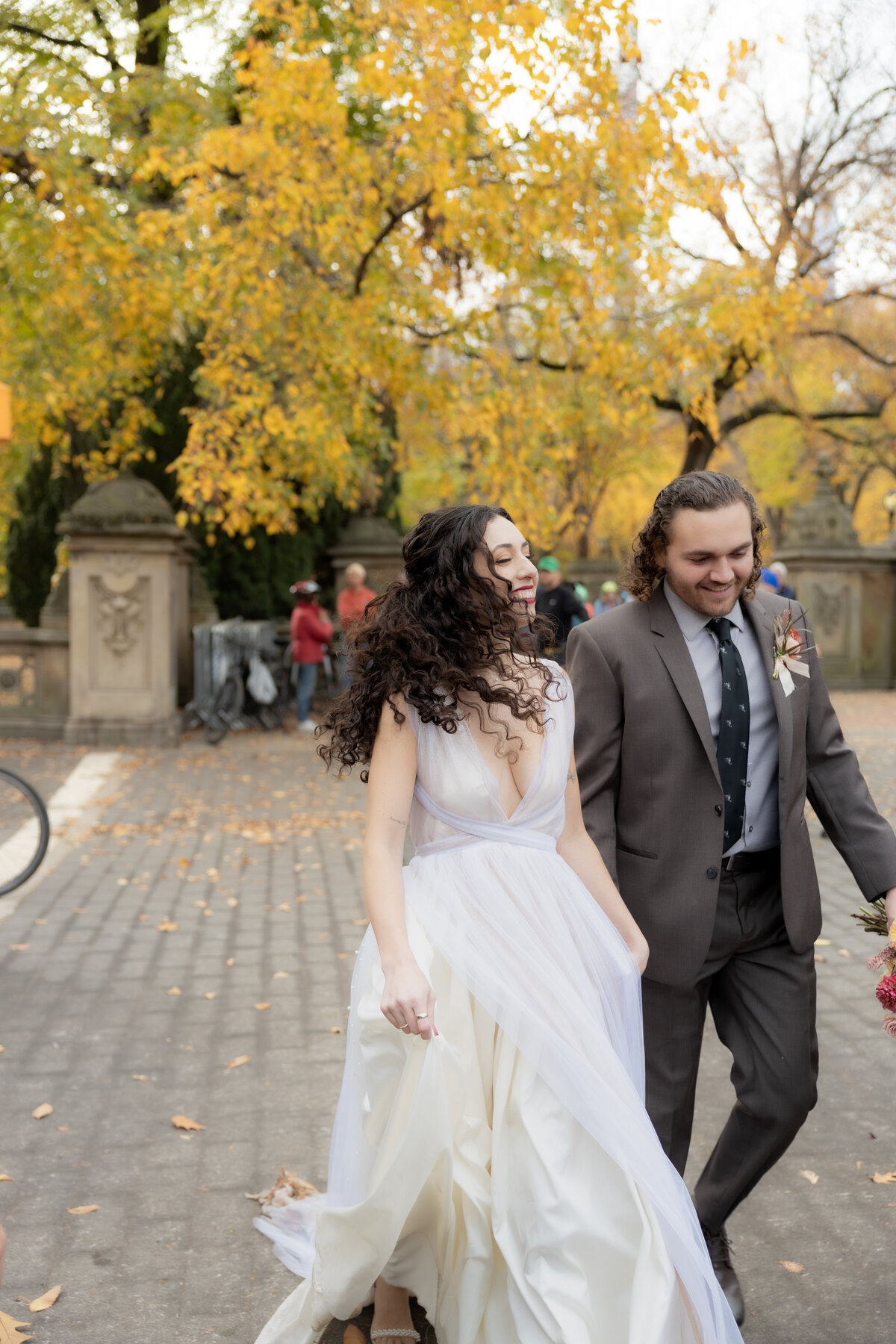 Bride and groom sharing a quiet moment under golden fall trees in Central Park.