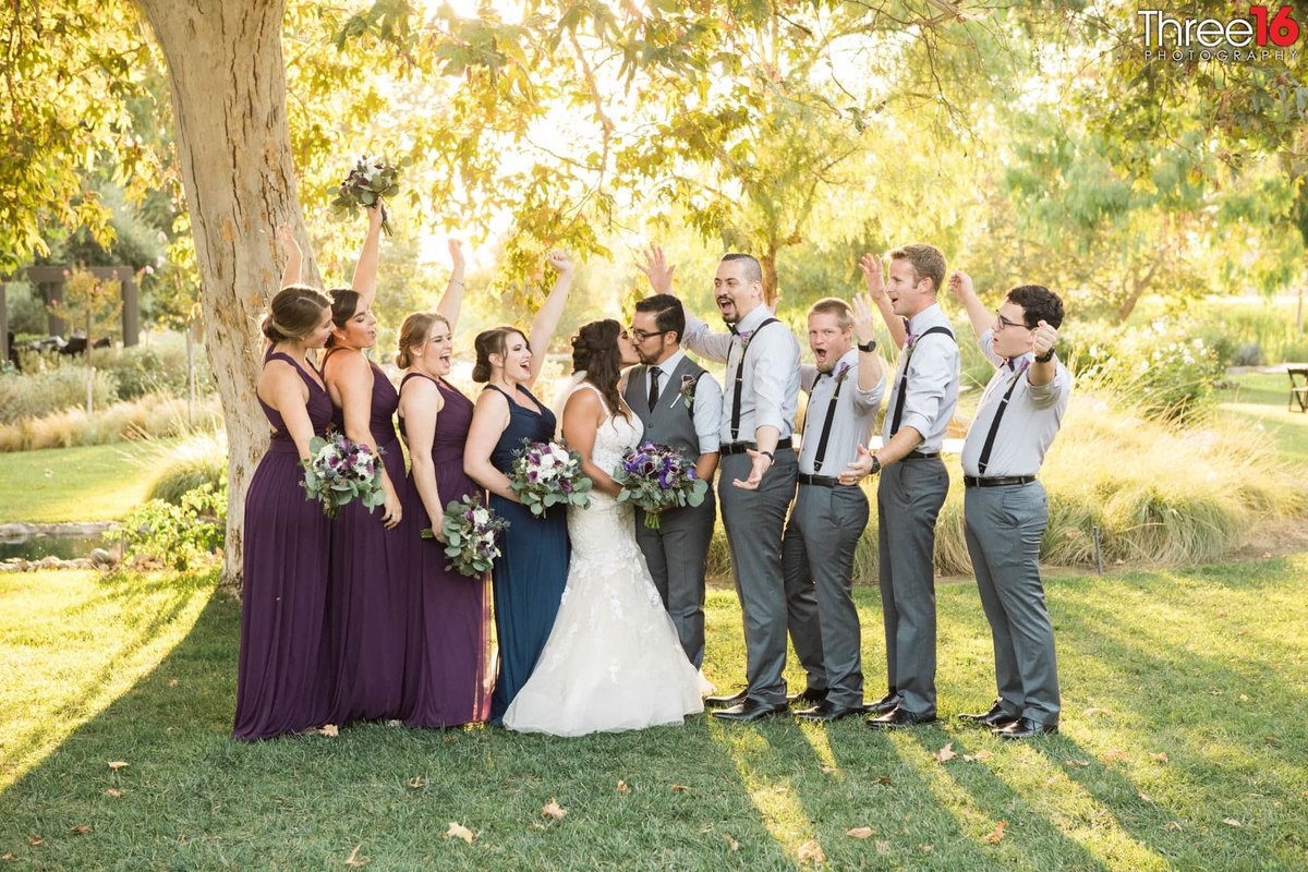 Bride and Groom kiss surrounded by wedding party