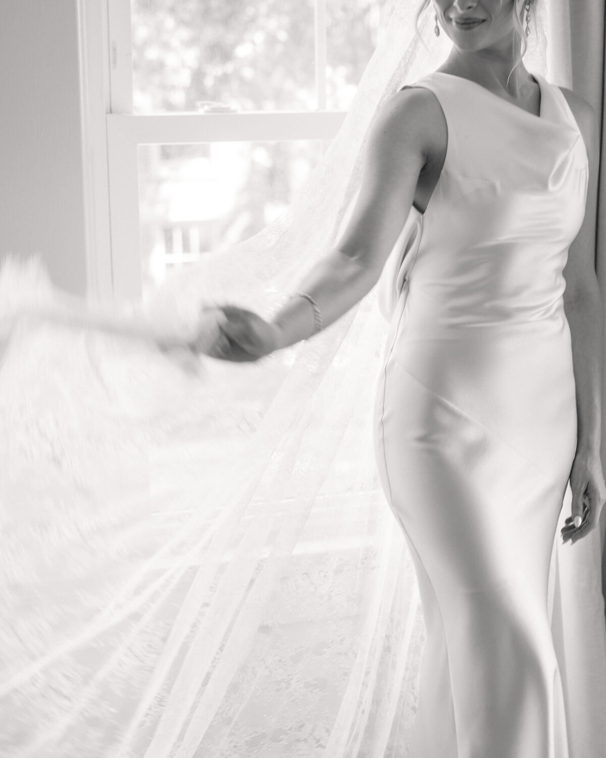 Artistic black-and-white shot of bride twirling veil at Dayton wedding, by Philadelphia wedding photographer.