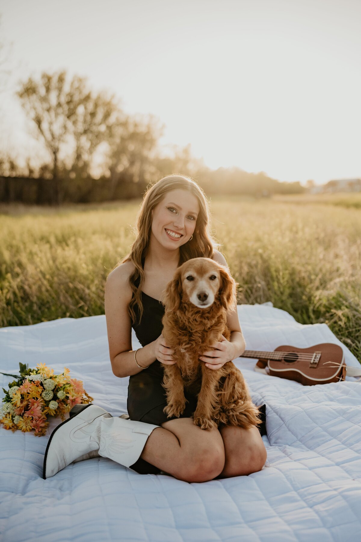 senior holding dog sitting in grass field, senior portrait photo session in amarillo texas