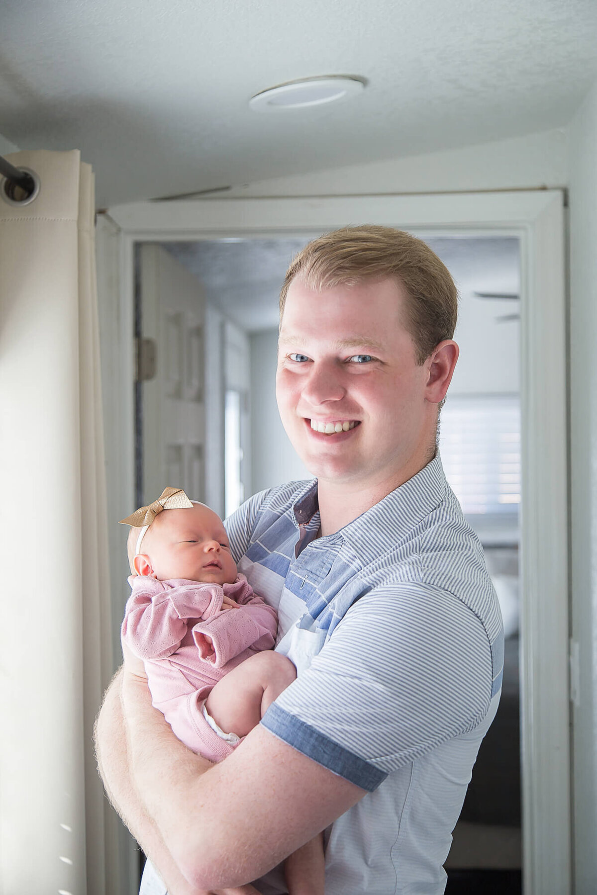 Father holding newborn baby girl during lifestyle in home newborn photography session