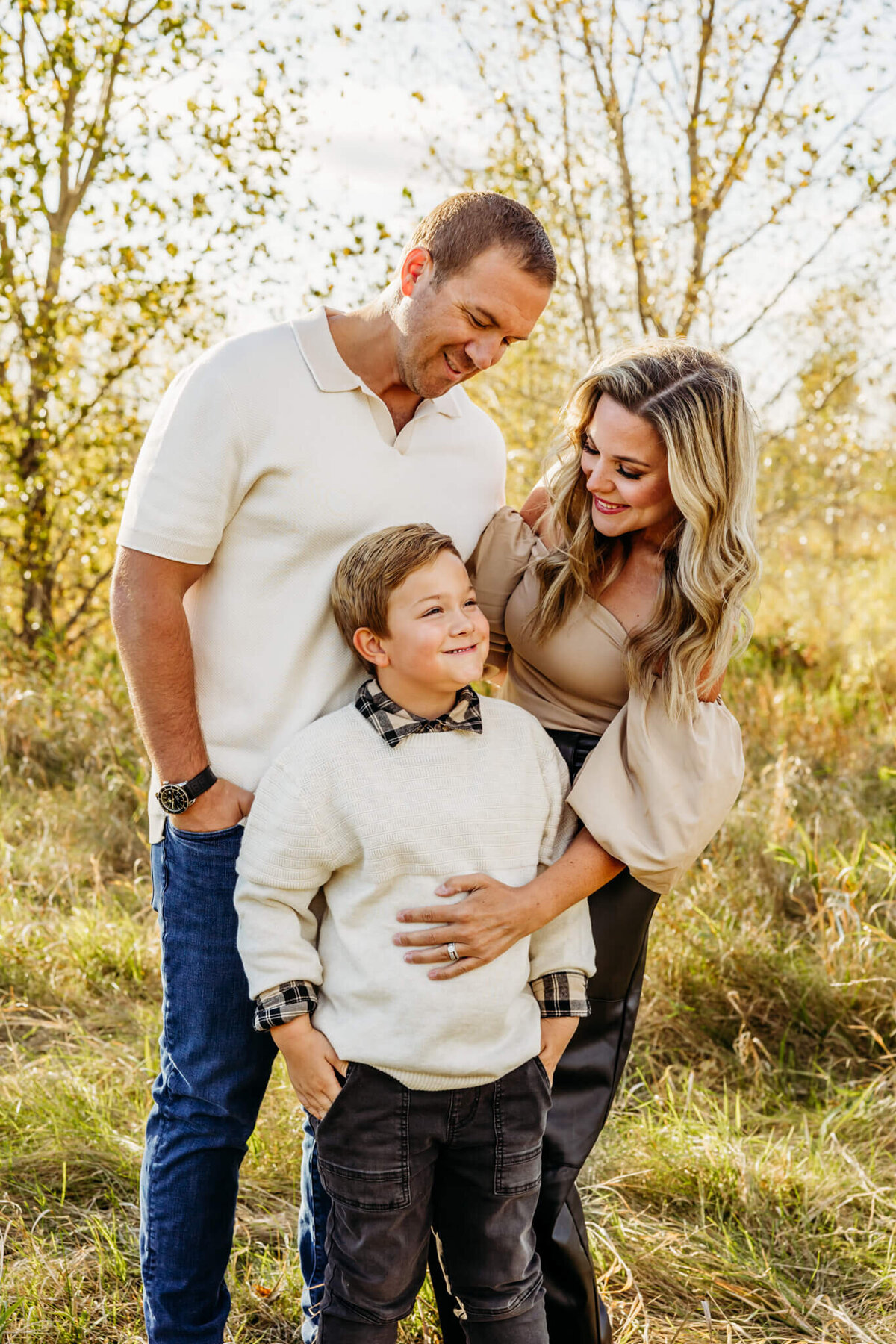 Father and mother holding their son and looking down at him as they laugh and enjoy their family photography session