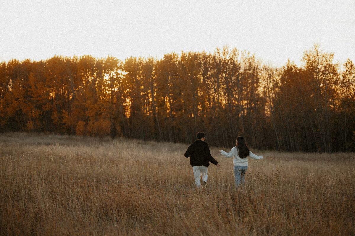 Photo of couple running in field during the fall 